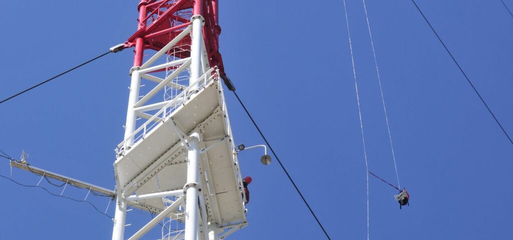 Person leaning over platform of the ZOTTO tower an device hanging on ropes