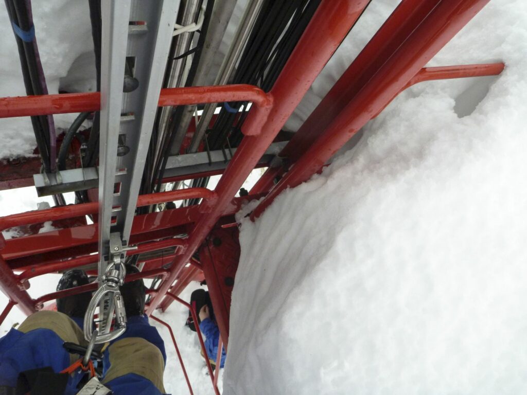 parts of 2 persons in blue snowsuits and climbing gear in the ladder shaft of the Tall Tower in freezing cold weather in winter