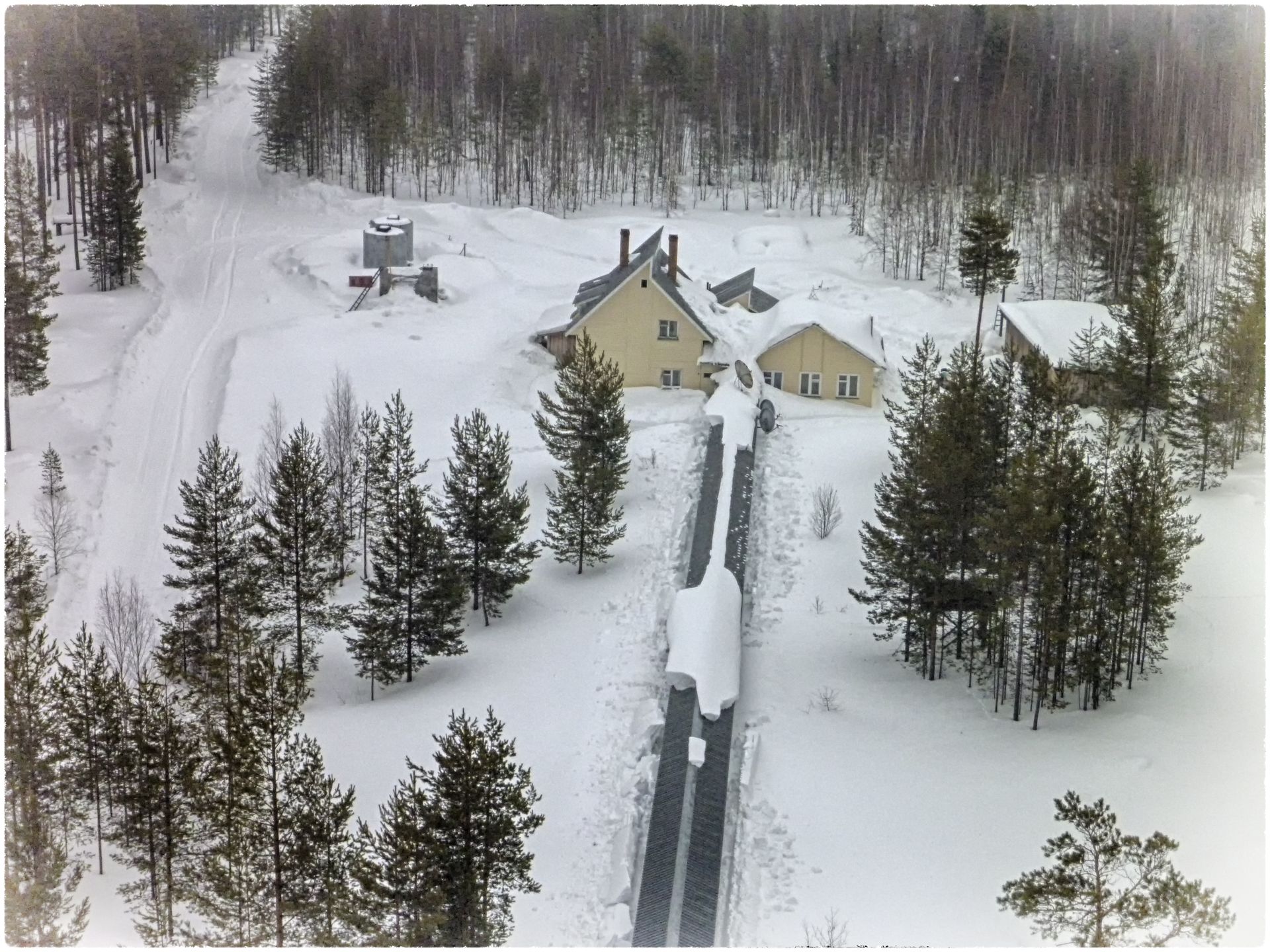 view from low height from the tower on snow-covered house and pergola in winter in Zotto
