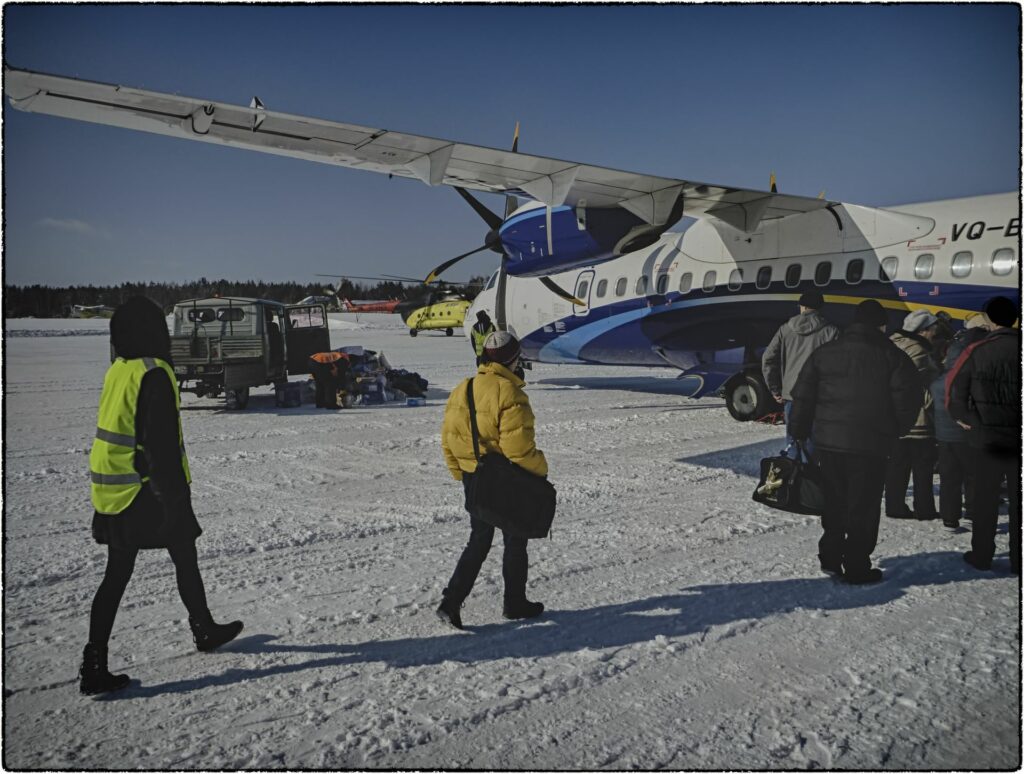 airplane in snow and waiting people