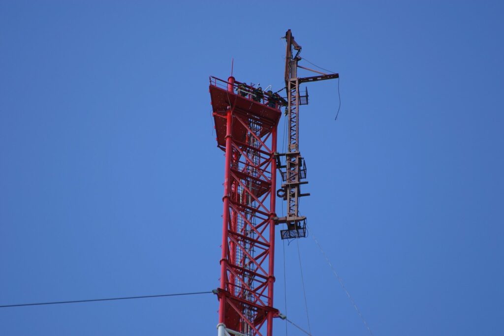 3 people and the erection-crane-on top of the so far built Zotto tall tower