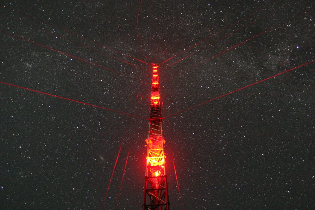 red illuminated tower before dark starry night with millions of stars